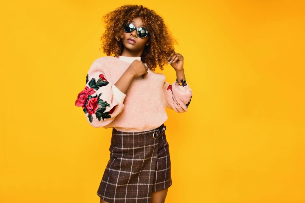 pexels-photo-794064-794064 Chic woman with afro hair in a floral sweater and plaid skirt posing confidently.